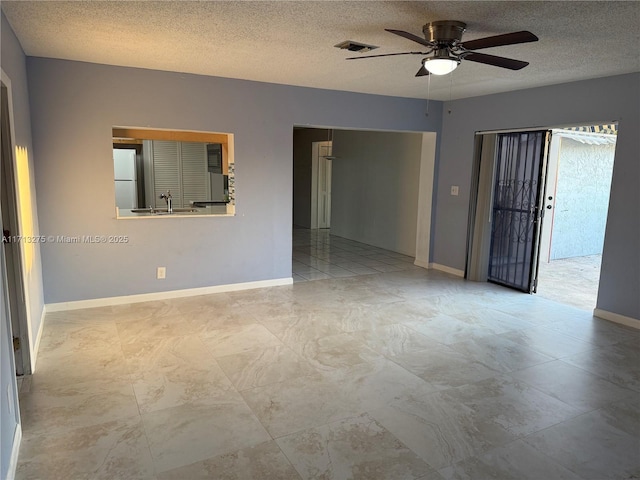 empty room featuring visible vents, baseboards, a sink, a ceiling fan, and a textured ceiling