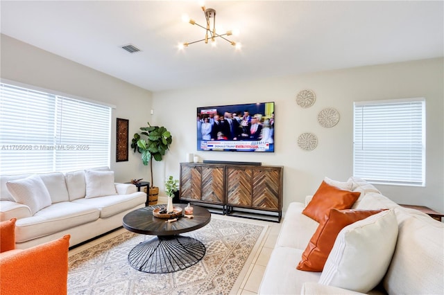 living room with light tile patterned floors, a healthy amount of sunlight, and a notable chandelier