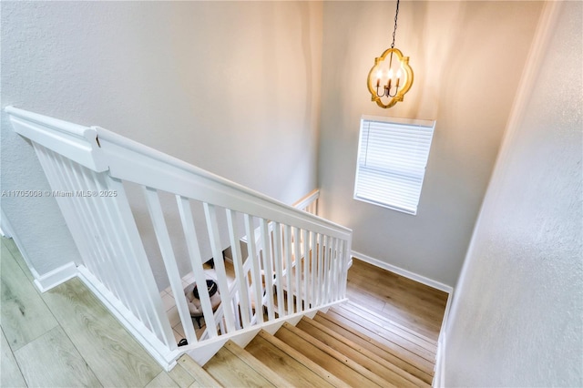 stairway featuring a chandelier and wood-type flooring