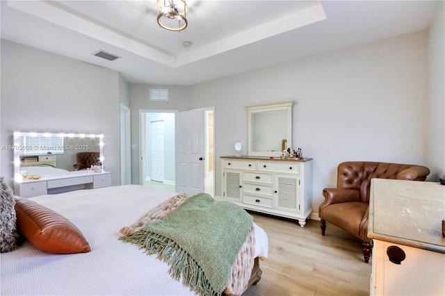 bedroom with a tray ceiling and light hardwood / wood-style flooring