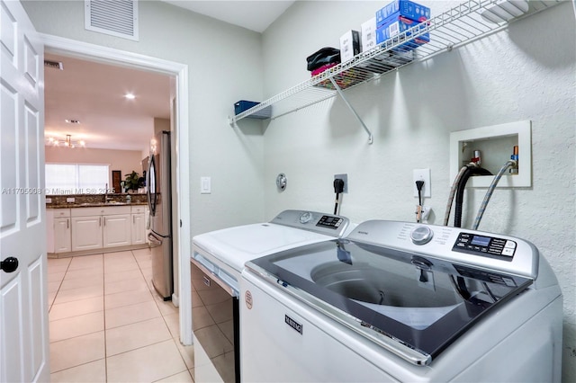 laundry room with light tile patterned floors, sink, and separate washer and dryer