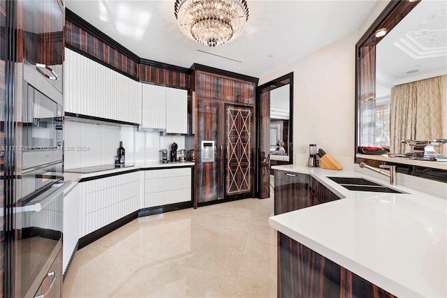 kitchen featuring dark brown cabinetry, black electric cooktop, a notable chandelier, and sink