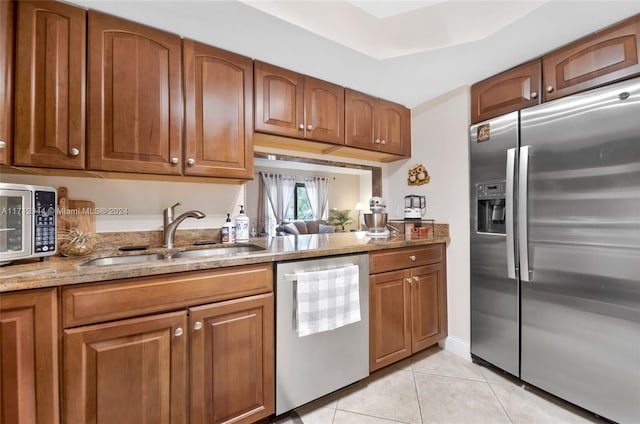 kitchen with light stone counters, sink, light tile patterned flooring, and appliances with stainless steel finishes