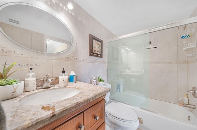 full bathroom with vanity, toilet, enclosed tub / shower combo, tile walls, and tasteful backsplash