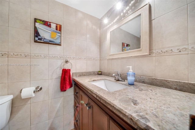 bathroom with vanity, tile walls, and toilet