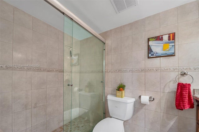 bathroom with a shower with shower door, tile walls, and toilet