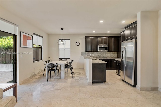 kitchen featuring light stone counters, plenty of natural light, stainless steel appliances, and decorative light fixtures