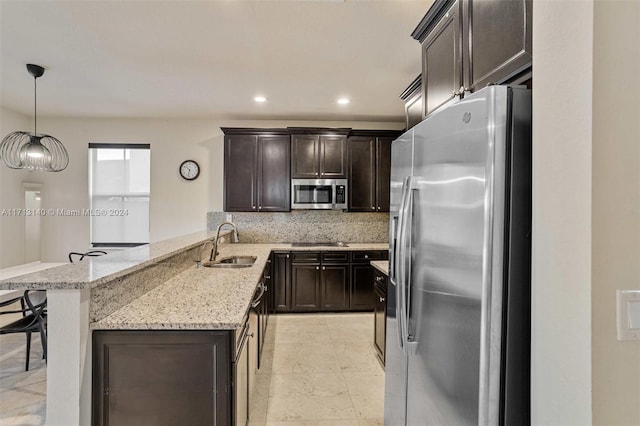 kitchen with sink, kitchen peninsula, pendant lighting, a kitchen bar, and appliances with stainless steel finishes