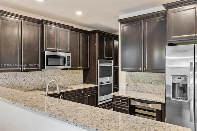 kitchen featuring wine cooler, backsplash, stainless steel appliances, and light stone counters