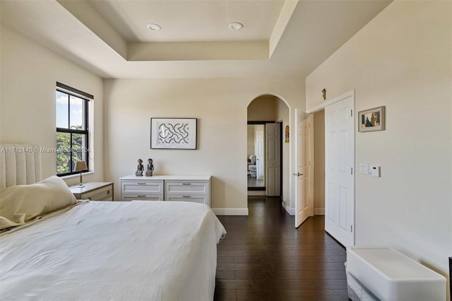 bedroom featuring a raised ceiling and dark hardwood / wood-style flooring