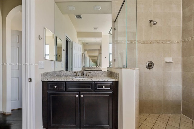 bathroom with tile patterned floors, vanity, and a tile shower