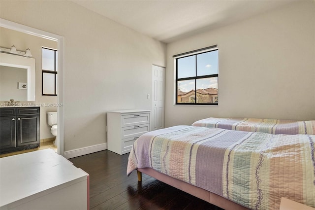 bedroom with dark hardwood / wood-style floors, ensuite bath, and sink