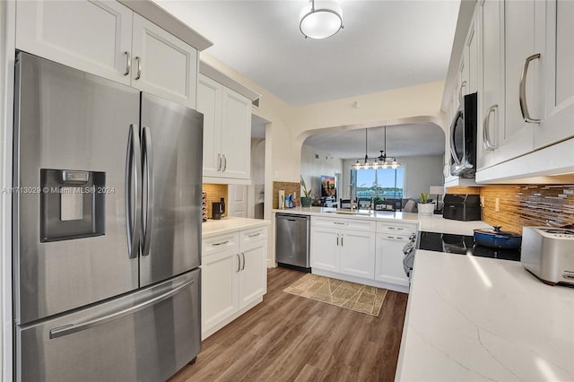 kitchen featuring white cabinets, appliances with stainless steel finishes, tasteful backsplash, and decorative light fixtures