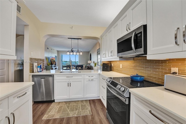 kitchen featuring sink, tasteful backsplash, decorative light fixtures, white cabinetry, and stainless steel appliances