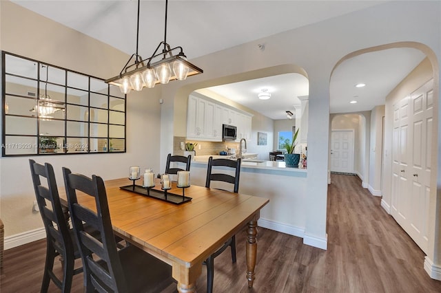 dining room with wood-type flooring, an inviting chandelier, and sink