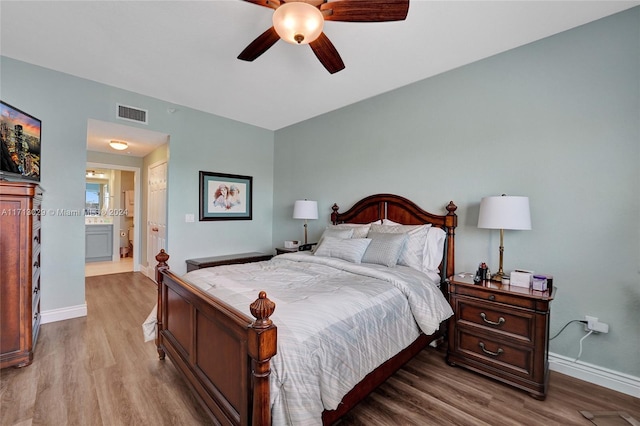 bedroom with ensuite bath, ceiling fan, and light hardwood / wood-style flooring