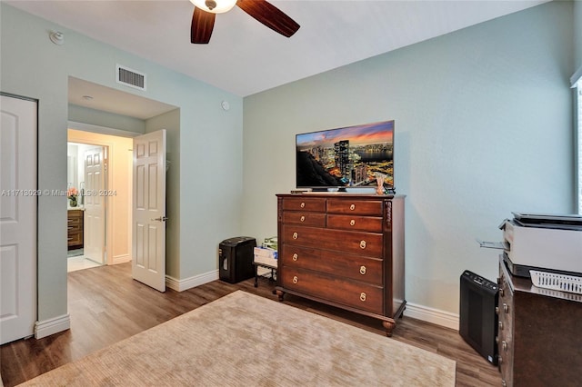 bedroom with ceiling fan, wood-type flooring, and ensuite bath