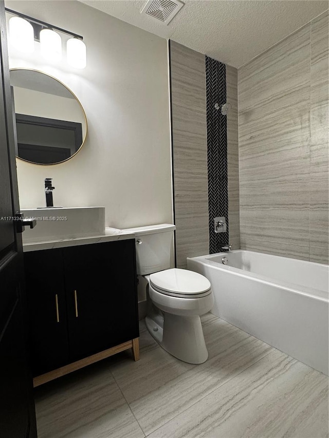 full bathroom featuring tiled shower / bath combo, tile patterned floors, a textured ceiling, toilet, and vanity