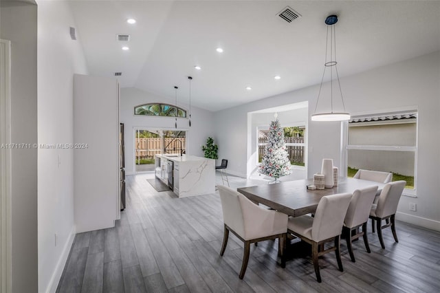 dining area featuring hardwood / wood-style flooring, vaulted ceiling, and a healthy amount of sunlight