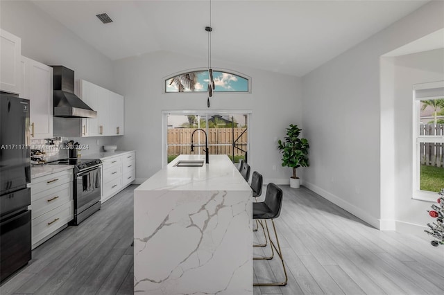 kitchen featuring wall chimney exhaust hood, sink, hanging light fixtures, lofted ceiling, and stainless steel electric range