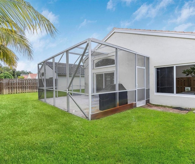 back of house featuring glass enclosure and a yard