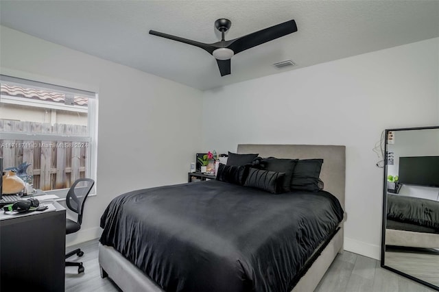 bedroom featuring ceiling fan, light wood-type flooring, and a textured ceiling