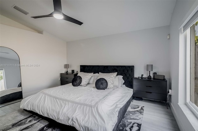 bedroom with ceiling fan, light hardwood / wood-style floors, and lofted ceiling