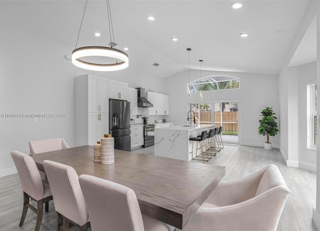 dining area with light hardwood / wood-style floors, sink, and vaulted ceiling