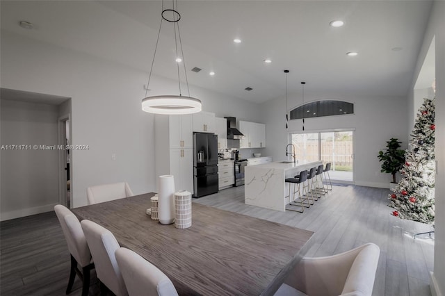 dining area featuring sink, high vaulted ceiling, and light hardwood / wood-style flooring