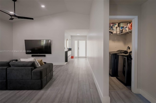 living room featuring washing machine and clothes dryer, ceiling fan, light hardwood / wood-style flooring, and vaulted ceiling