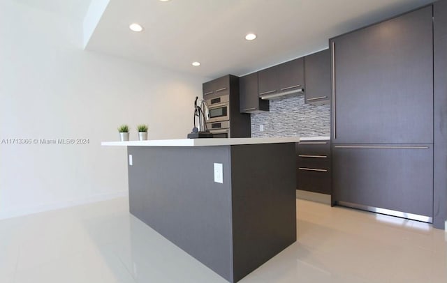 kitchen featuring a kitchen island, light tile patterned flooring, and backsplash