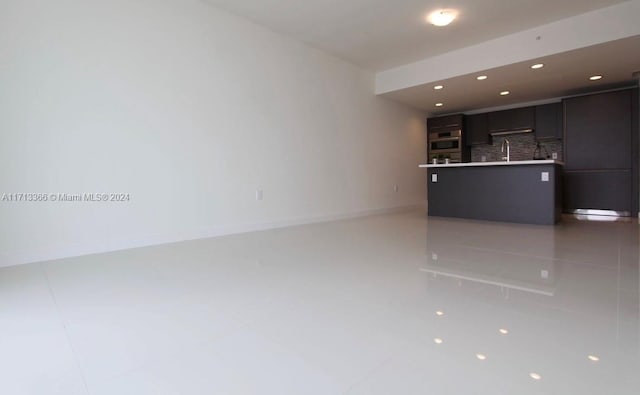 kitchen featuring a center island with sink, stainless steel oven, and tasteful backsplash