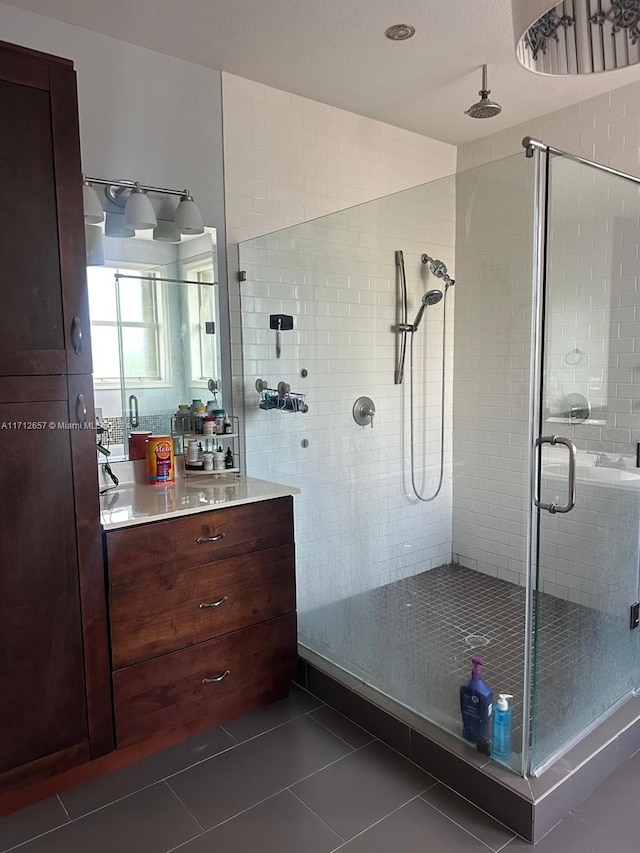 bathroom featuring tile patterned flooring, vanity, and a shower with shower door