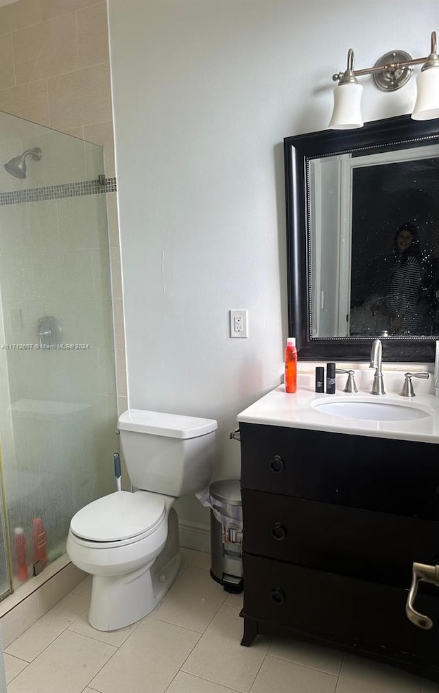 bathroom with tile patterned floors, vanity, tiled shower, and toilet