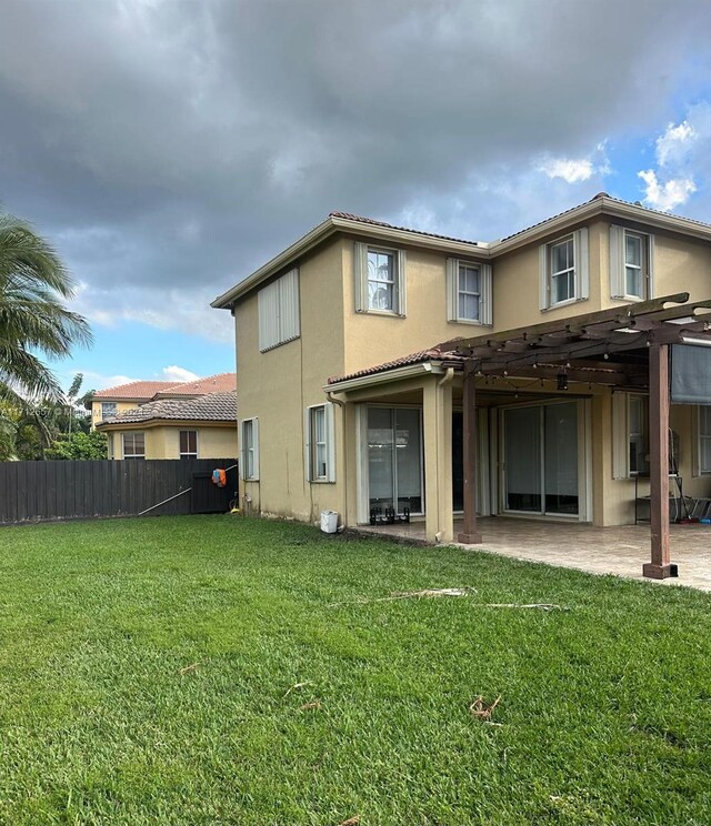 back of house featuring a pergola, a patio, and a lawn