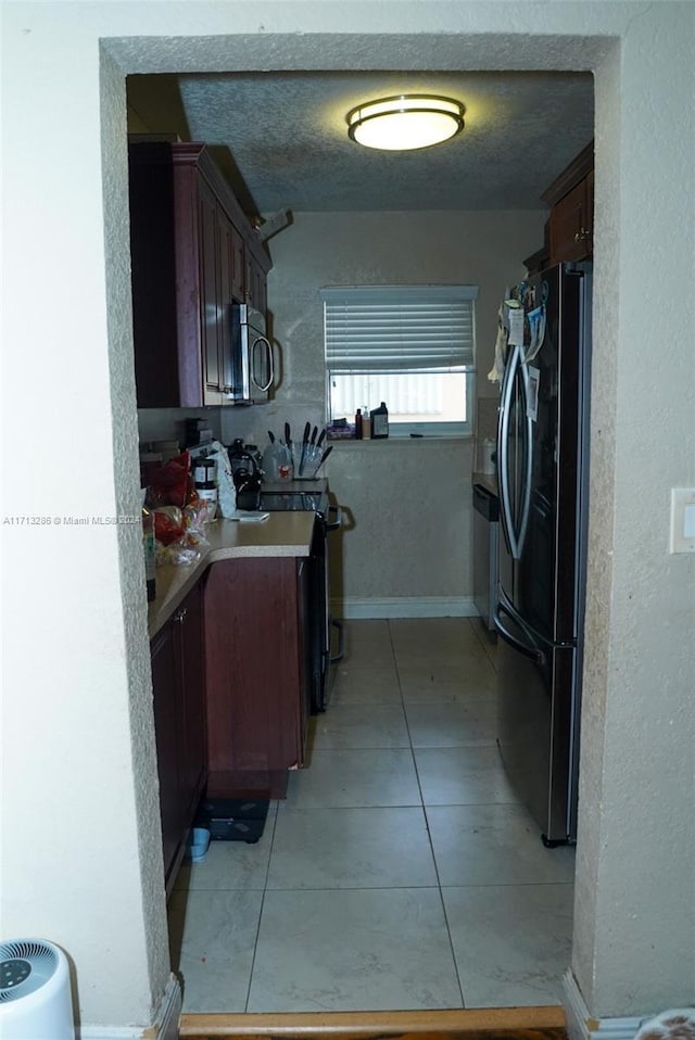 kitchen with light tile patterned floors, a textured ceiling, and appliances with stainless steel finishes