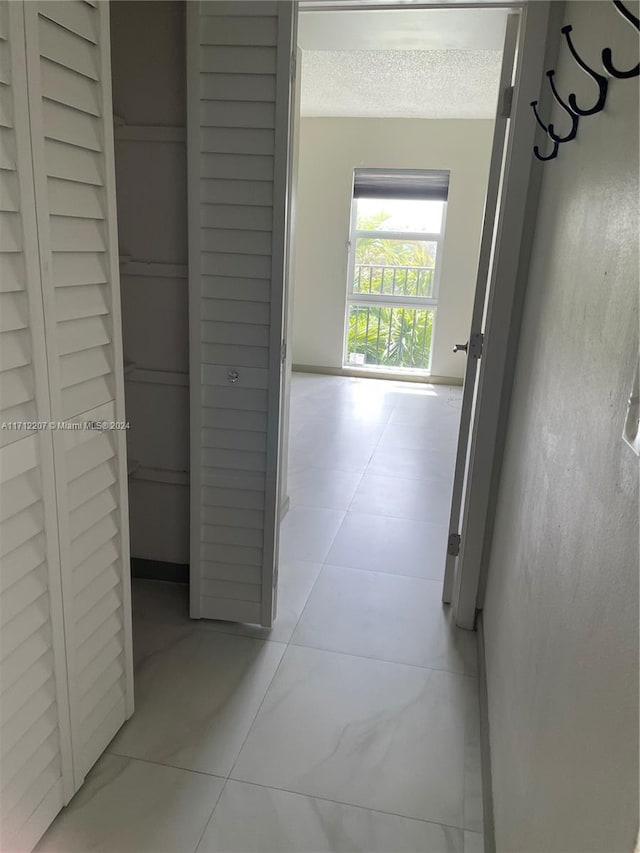 corridor with light tile patterned floors and a textured ceiling