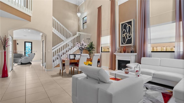 living room with a high ceiling, light tile patterned floors, and crown molding