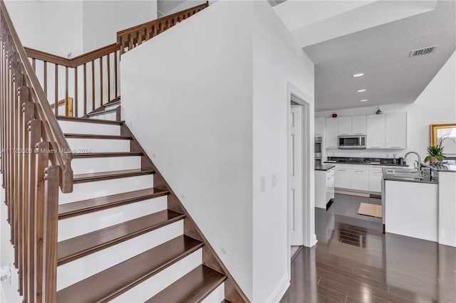 stairs featuring hardwood / wood-style flooring and sink