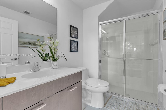 bathroom with tile patterned floors, vanity, toilet, and an enclosed shower