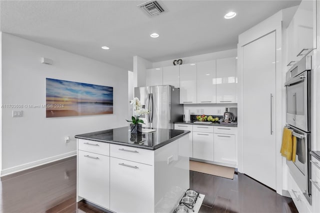 kitchen with a center island, stainless steel fridge, double oven, dark hardwood / wood-style flooring, and white cabinetry