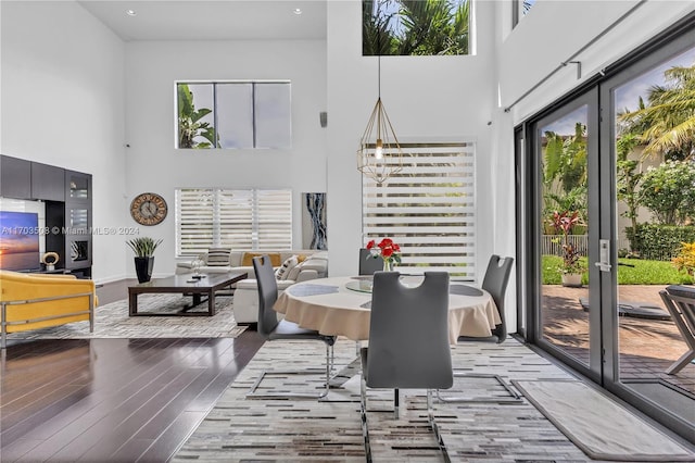 dining area featuring hardwood / wood-style flooring, a notable chandelier, and a high ceiling