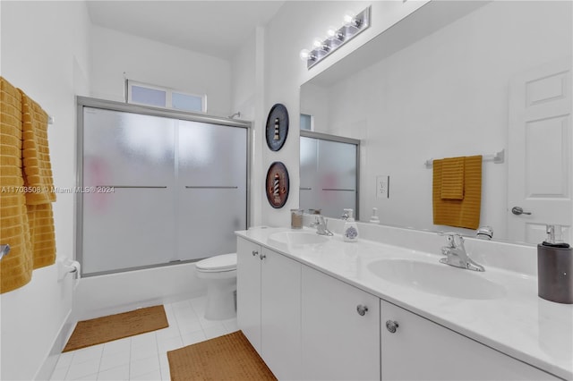 full bathroom with tile patterned floors, vanity, bath / shower combo with glass door, and toilet