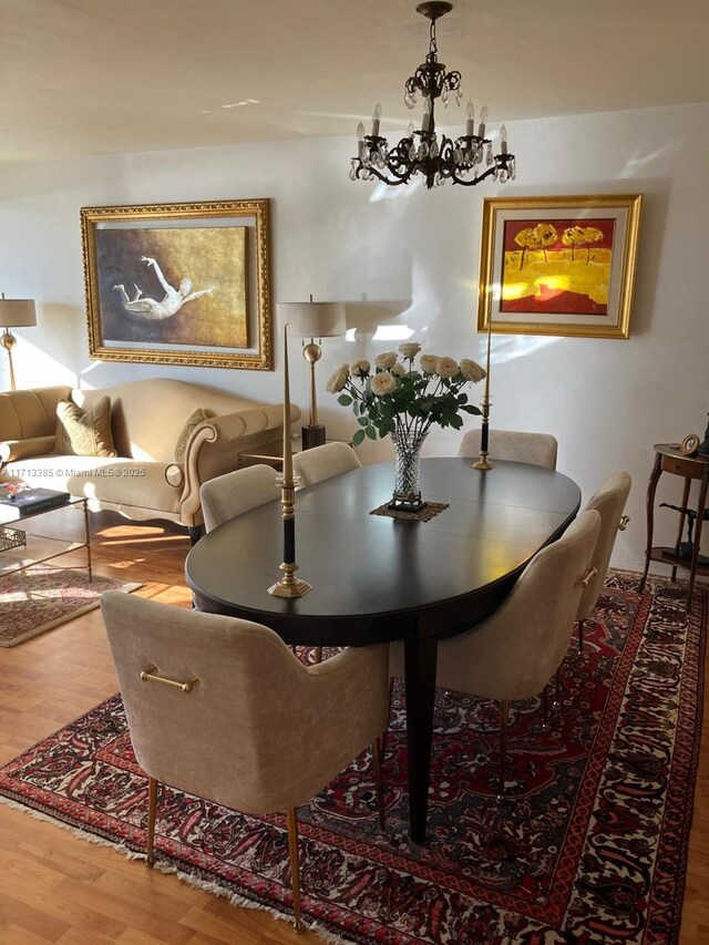 dining space featuring wood-type flooring and a notable chandelier