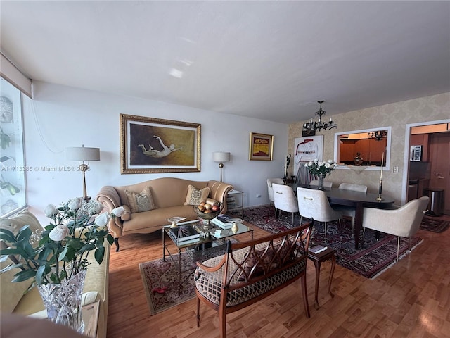 living room with wallpapered walls, wood finished floors, and an inviting chandelier