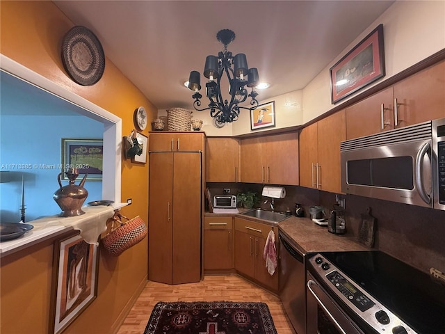 kitchen featuring sink, backsplash, light hardwood / wood-style floors, stainless steel appliances, and an inviting chandelier