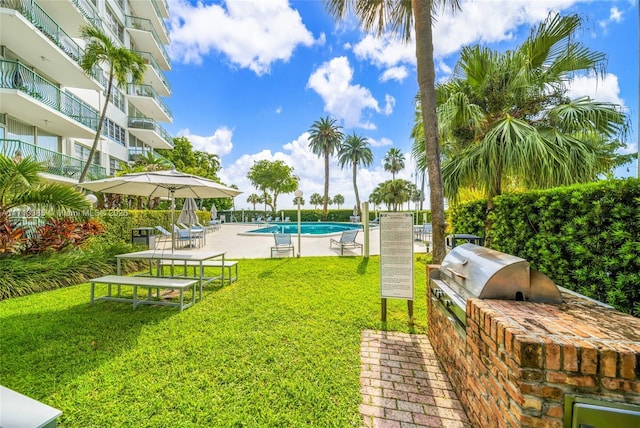 view of yard featuring a community pool, exterior kitchen, and a patio