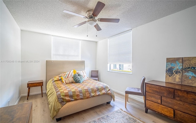 bedroom with a textured ceiling, light hardwood / wood-style floors, and ceiling fan