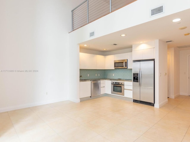 kitchen featuring white cabinets, sink, decorative backsplash, light tile patterned flooring, and stainless steel appliances