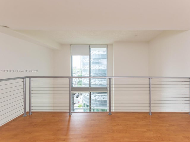 empty room with floor to ceiling windows and wood-type flooring